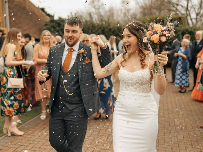 A happy bride and groom walking through confetti at their weddings