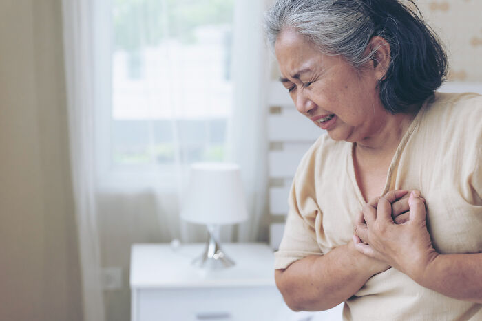 A senior woman clutches her chest, looking distressed, revealing serious health issues that seemed innocent.
