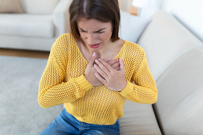 A woman clutches her chest with a pained expression, highlighting serious medical issues that started innocently.