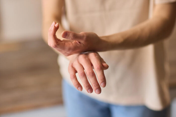 A person holds their wrist, showing discomfort in an everyday action that might indicate serious medical issues.