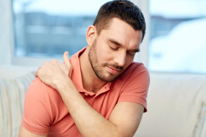 A man rubs his shoulder in pain, highlighting serious medical issues that started seemingly innocent.