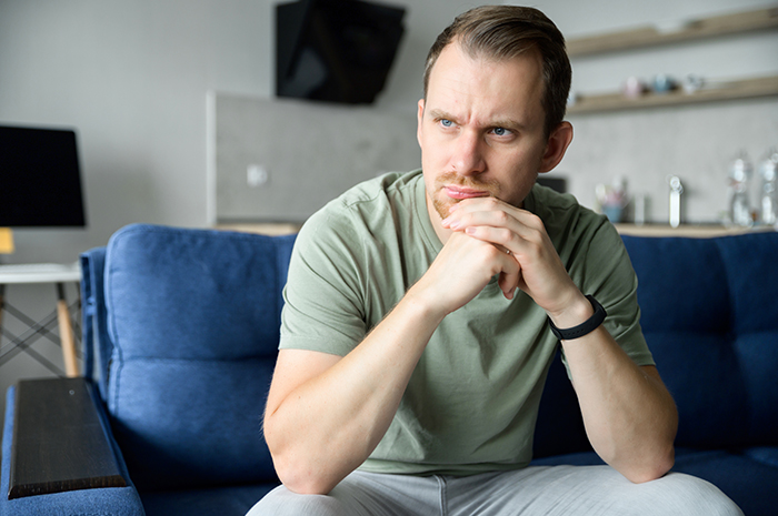 Pensive man sitting on a sofa, representing a BIL who brings a different GF to family Thanksgiving. Pensive man sitting on a sofa, representing a BIL who brings a different GF to family Thanksgiving.