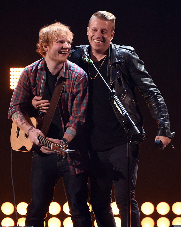 Ed Sheeran and Macklemore happily pose together on stage during a performance.