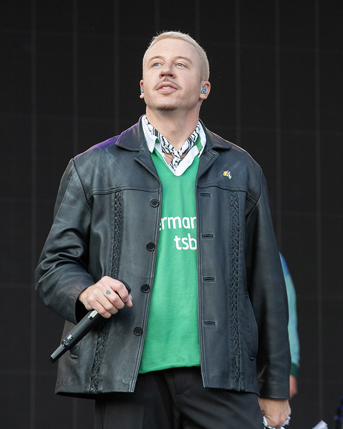 Macklemore performing, allegedly removed from Ed Sheeran Tour, facing backlash.