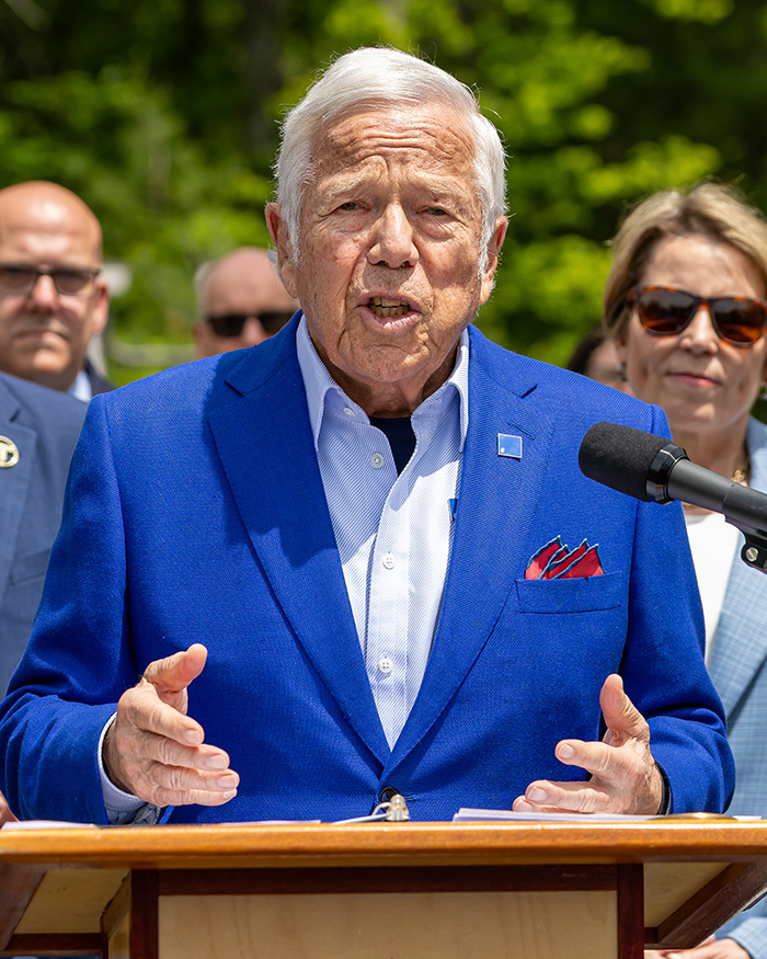 Billionaire speaks at a podium, central to Macklemore's removal from the Ed Sheeran tour.