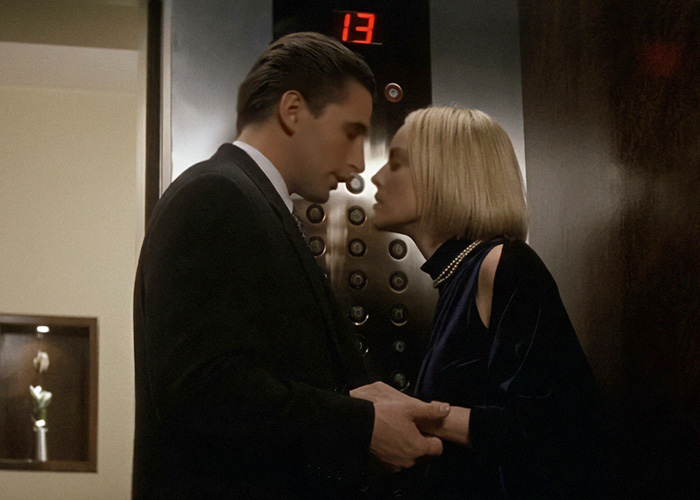 Billy Baldwin and actress in an elevator, about to kiss on camera.