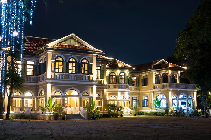 A grand mansion illuminated at night, a surprising thing wealthy people buy for luxury.