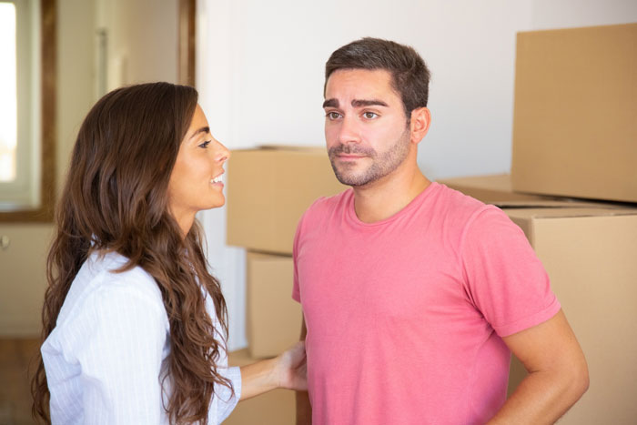 A young woman talks to her jobless BF while surrounded by moving boxes.
