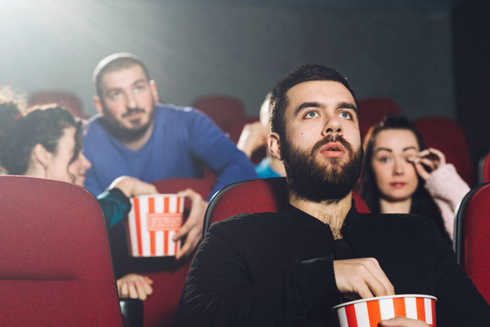 Group of people watching horror movie in theater eating popcorn