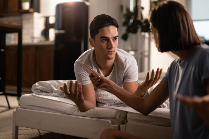 Couple in bedroom having serious discussion about obsession