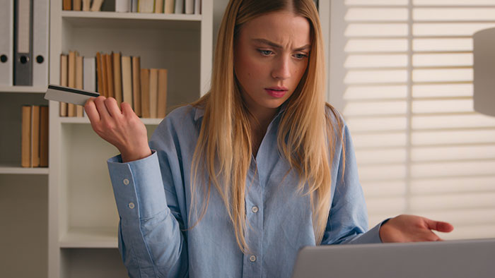 A woman looking frustrated while holding a credit card, refusing to bail out bro who squandered inheritance. A woman looking frustrated while holding a credit card, refusing to bail out bro who squandered inheritance.