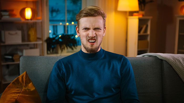 Image of a man on a couch with a disgusted expression, symbolizing frustration from inheritance squandered by brother. Image of a man on a couch with a disgusted expression, symbolizing frustration from inheritance squandered by brother.