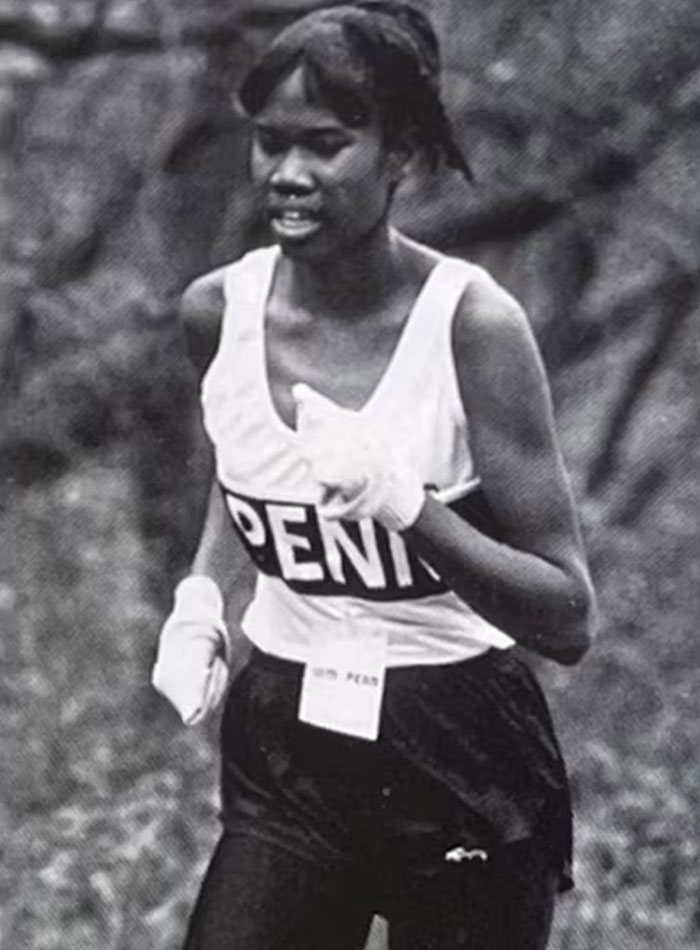 Black and white photo of a female rising track star running in race
