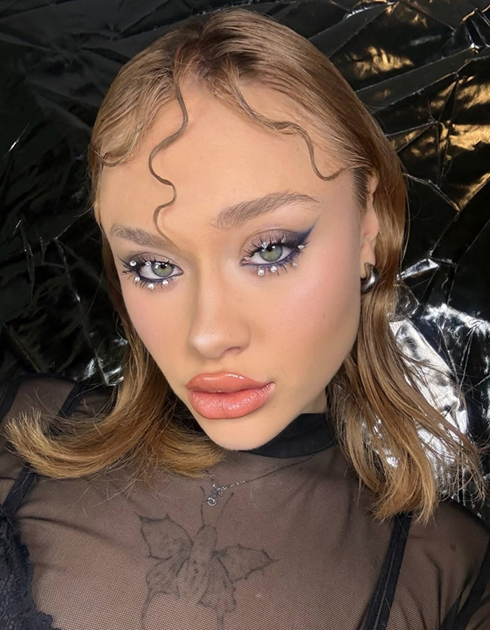 Beauty influencer with creative eye makeup and wavy hair