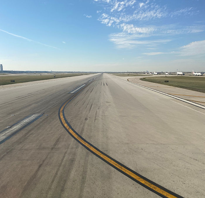 Airport runway stretching into the distance under a blue sky, emphasizing the story of the two graves Airport runway stretching into the distance under a blue sky, emphasizing the story of the two graves
