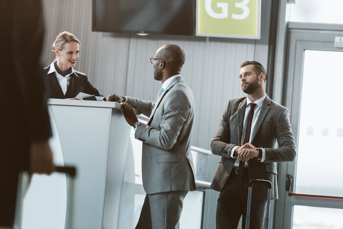 A flight attendant assisting passengers at a gate, illustrating things a passenger could do.