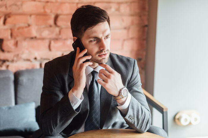 Businessman on a phone call, looking serious, possibly reacting to an awkward first date story.