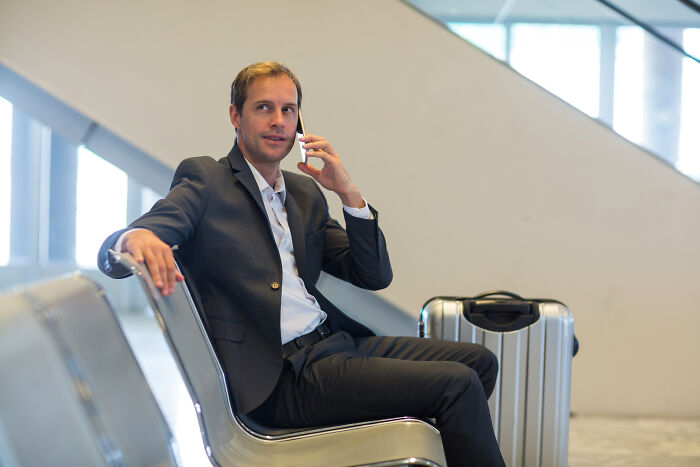 Businessman in suit sitting and talking on phone at airport