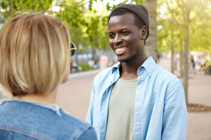 A man smiles while speaking to a woman, turned away by a realtor for not fitting the neighborhood. A man smiles while speaking to a woman, turned away by a realtor for not fitting the neighborhood.