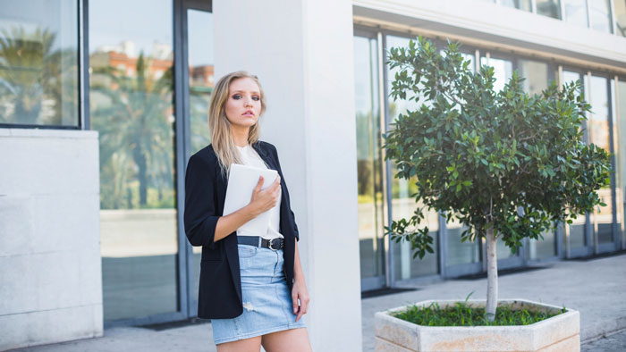 A realtor stands outside a modern building, holding a tablet, exemplifying a man turned away by a realtor. A realtor stands outside a modern building, holding a tablet, exemplifying a man turned away by a realtor.