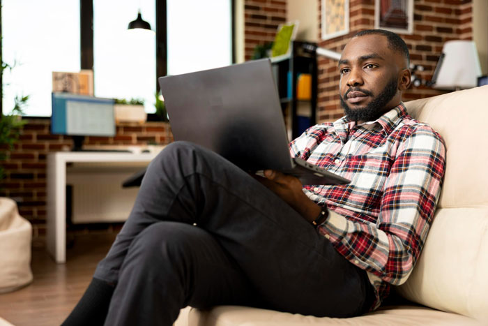 A man with a laptop, looking thoughtful, conveying he was turned away by a realtor. A man with a laptop, looking thoughtful, conveying he was turned away by a realtor.