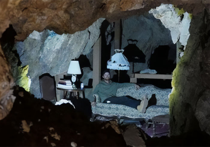 A man relaxing on a couch inside a cave in his ghost town A man relaxing on a couch inside a cave in his ghost town