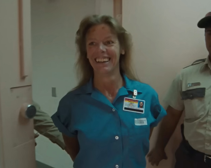 Disturbing criminal Aileen Wuornos smiles while escorted by a prison guard. Disturbing criminal Aileen Wuornos smiles while escorted by a prison guard.