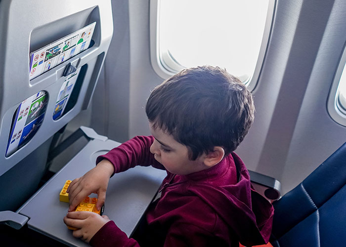 A child playing with yellow blocks at an airplane window seat, highlighting an airplane window seat scenario. A child playing with yellow blocks at an airplane window seat, highlighting an airplane window seat scenario.