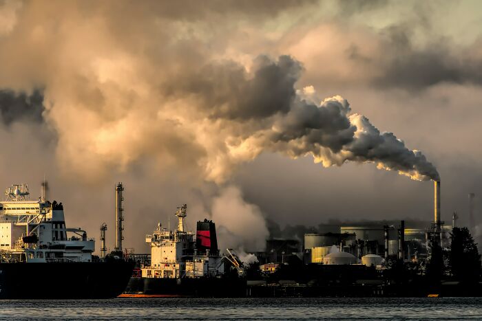 Industrial smokestacks emitting thick clouds of smoke, illustrating environmental scandals and pollution.