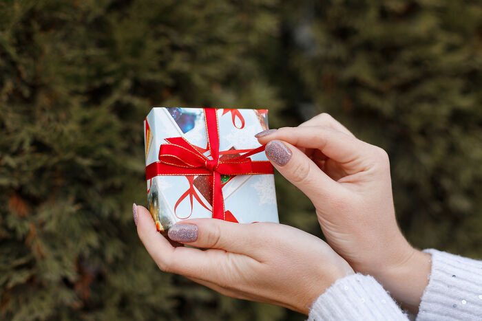 Hands gently unwrapping a small gift box, showcasing satisfying stories of giving.