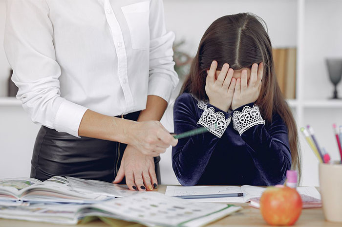 Student finds a perfect way to drive her teacher crazy. A sad student crying while the teacher points at the book. Student finds a perfect way to drive her teacher crazy. A sad student crying while the teacher points at the book.