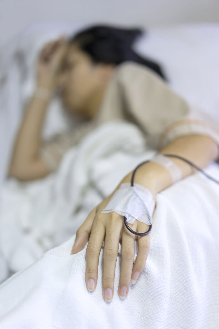 A person in a hospital bed with an IV drip, representing extreme illness and sickness.