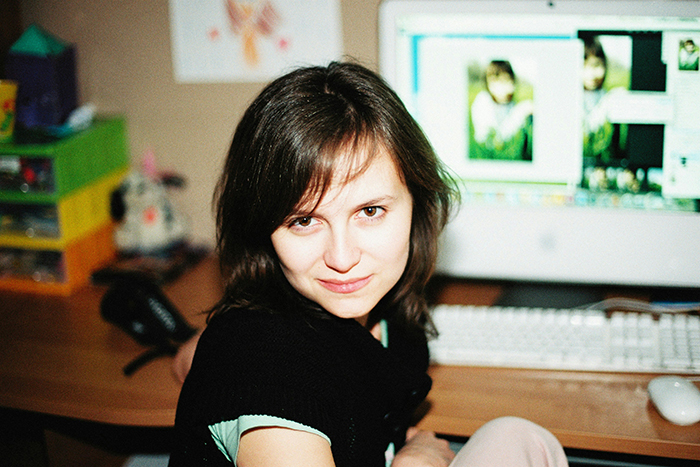 A woman smiling at her desk in front of a computer, relating to fake friend story