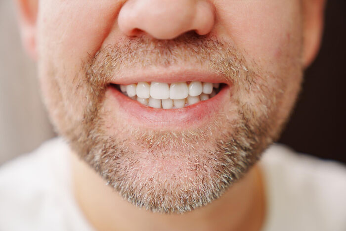 Close-up of a smiling man with a beard, showing healthy teeth, relating to historical facts.