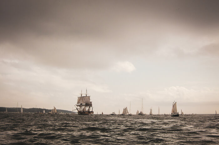 Tall ships sailing on the ocean under a cloudy sky, illustrating historical facts about maritime travel.