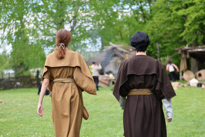 Two people in historical robes walking away in a field, depicting historical facts about past cultures.