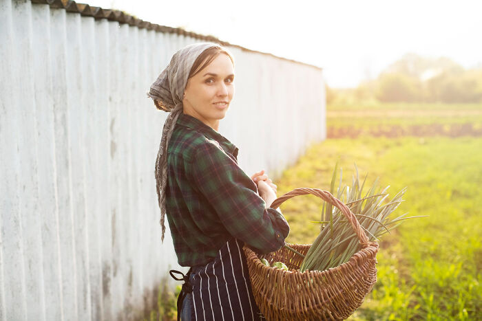A woman with a headscarf and apron, holding a basket of produce, representing historical facts about farming.