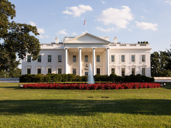 The White House, a symbol of American history, with a fountain and red flowers, highlighting historical facts.