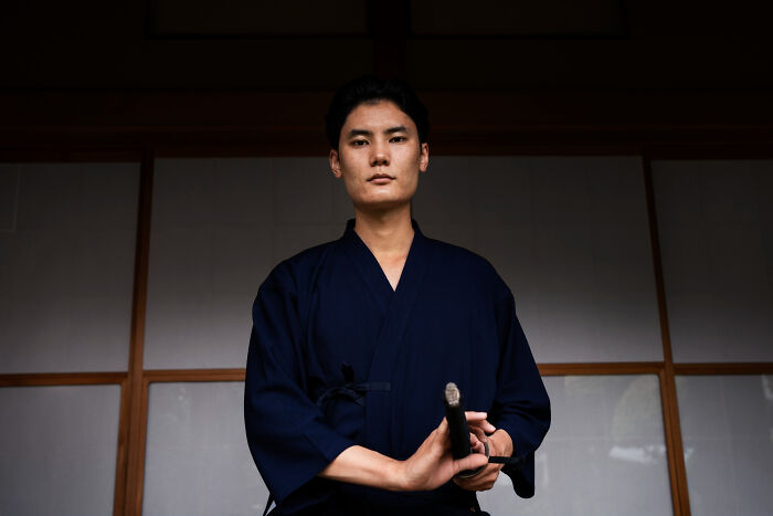 A man in traditional Japanese attire holding a sword, representing historical facts and martial arts.