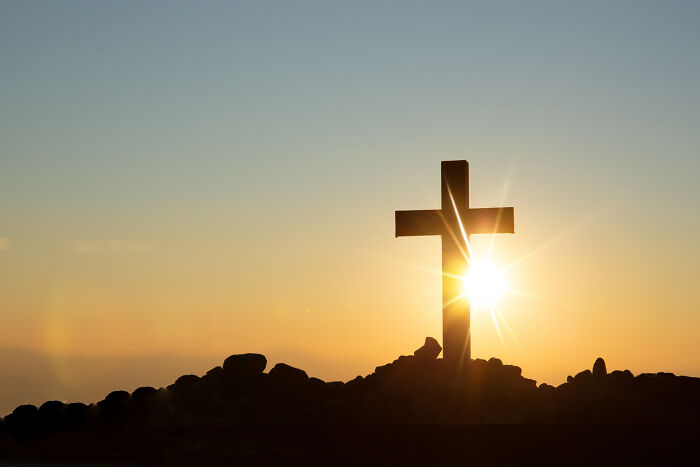 A historical facts cross silhouetted against a setting sun, symbolizing historical facts.