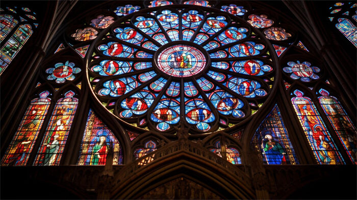A large, intricate stained-glass rose window, showcasing historical architectural design.