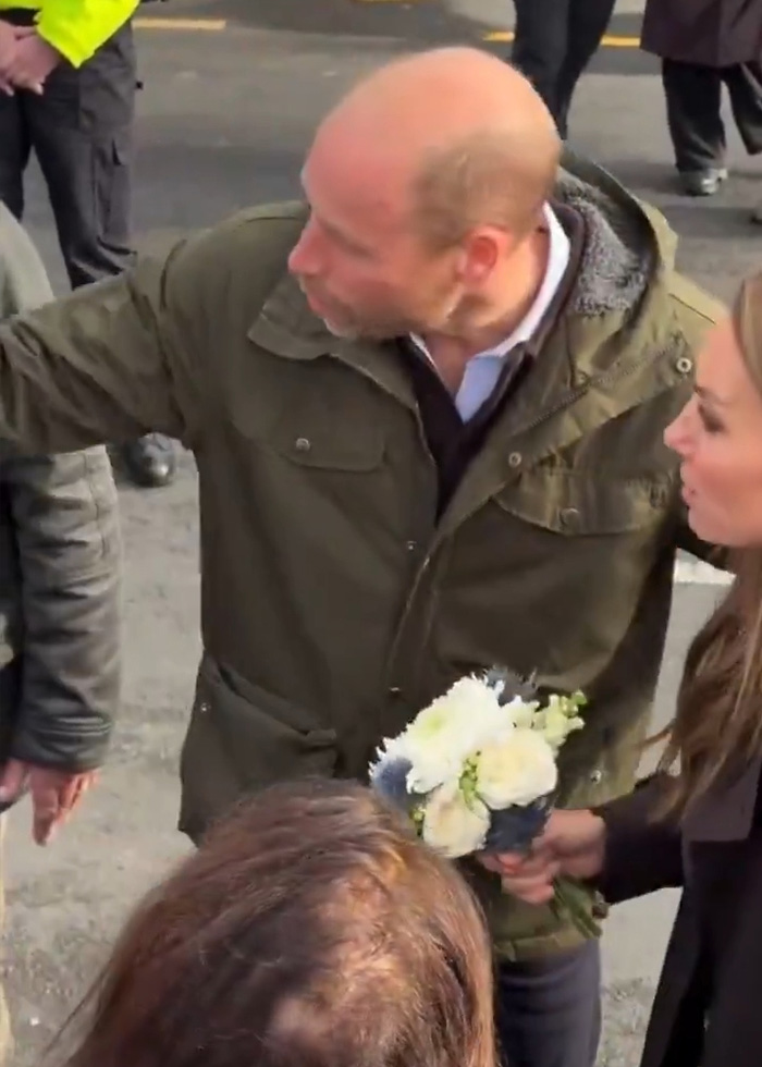 Prince William and Kate Middleton in public, with William looking at Kate holding a bouquet, showing public behavior.