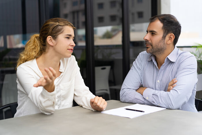 A woman explaining her ideas to a male colleague who is listening, discussing subtle sexism at work