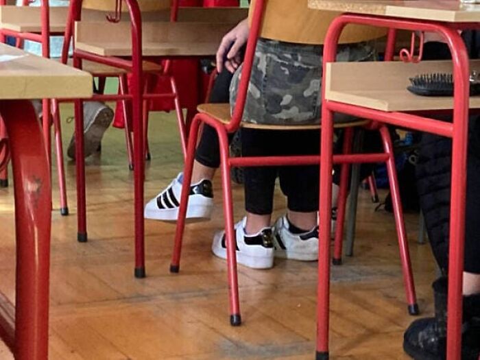 Confusing perspective of a student sitting on a classroom chair with multiple legs visible