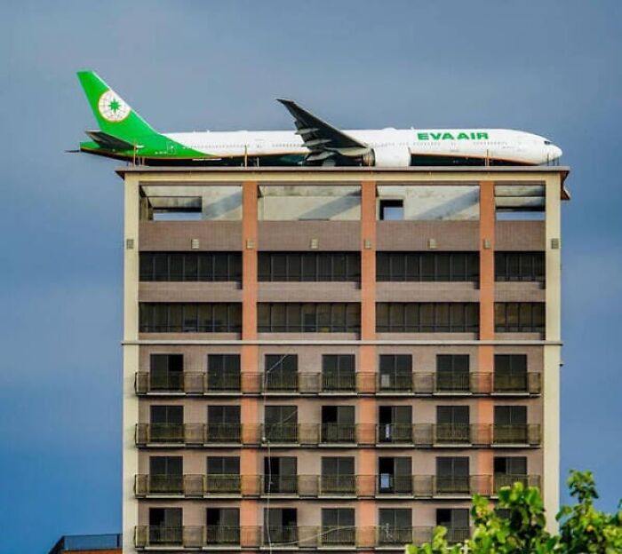 An EVA Air plane appears to be parked on the roof of a high-rise building, creating a confusing perspective.