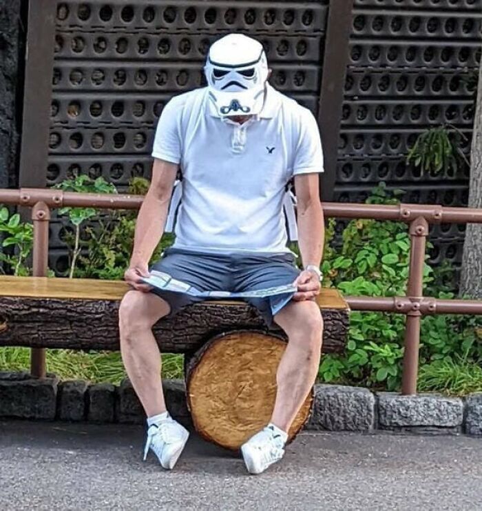 A man with a stormtrooper helmet on his head looking at a map