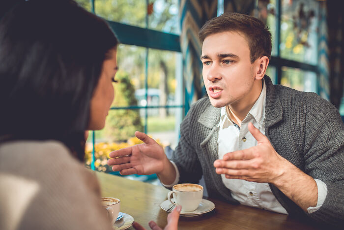 A man talking animatedly to a woman on a first date, suggesting an awkward first date.