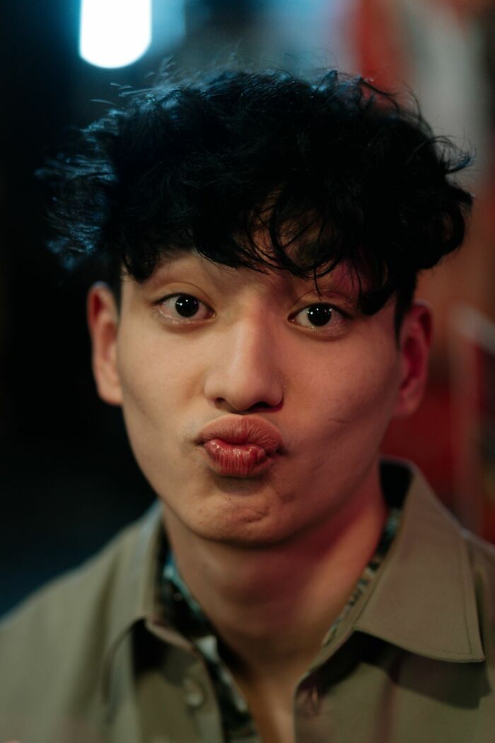 A close-up of a young male coworker making a funny face with puckered lips in a casual setting