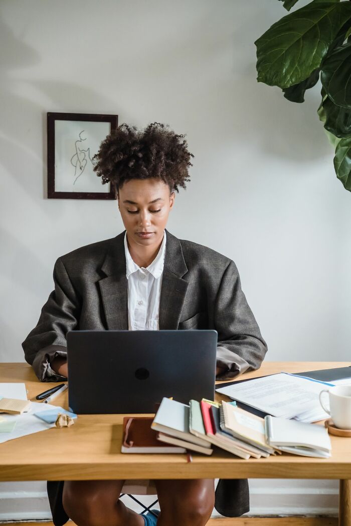 A female coworker sitting at a desk with a laptop, looking focused while working in an office setting