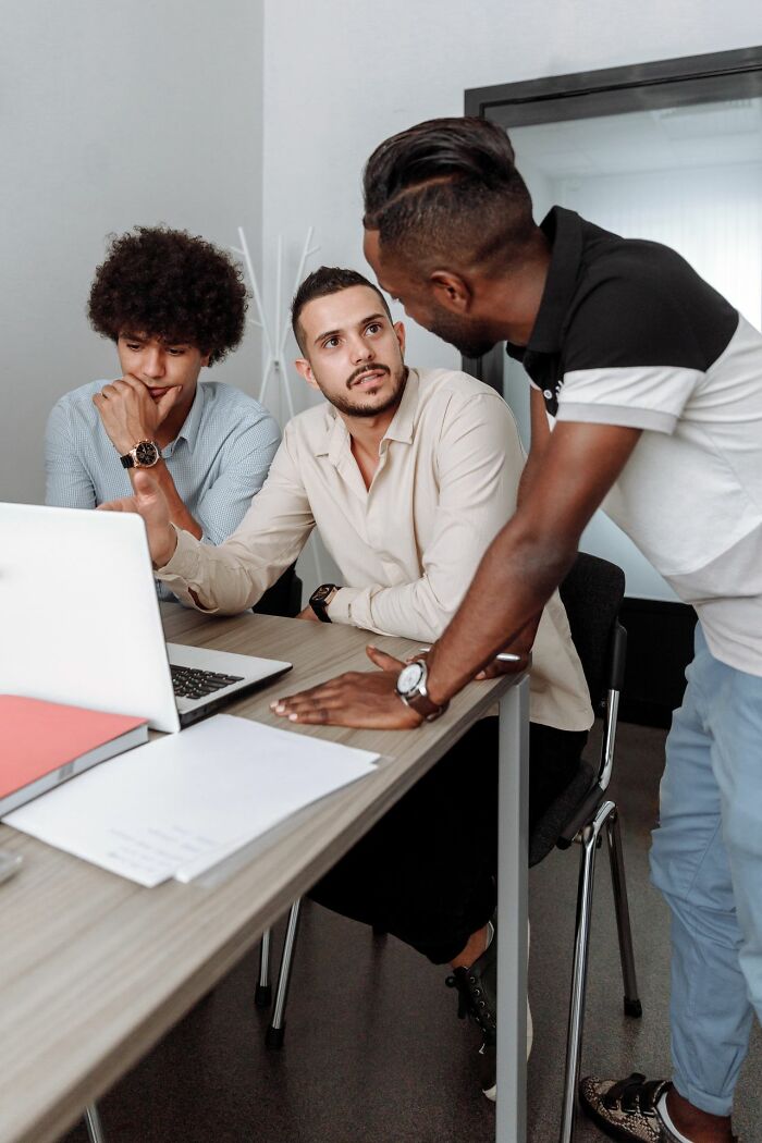 Male coworkers collaborating on a laptop at an office desk